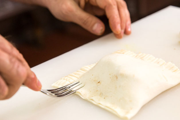 Using a fork to press down the edges of the pastry 