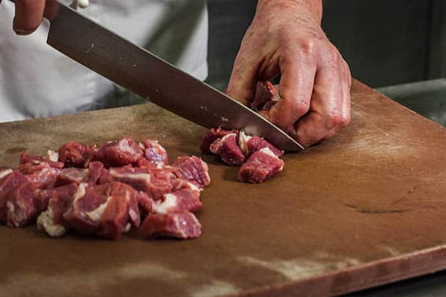 Cutting raw meat into cubes