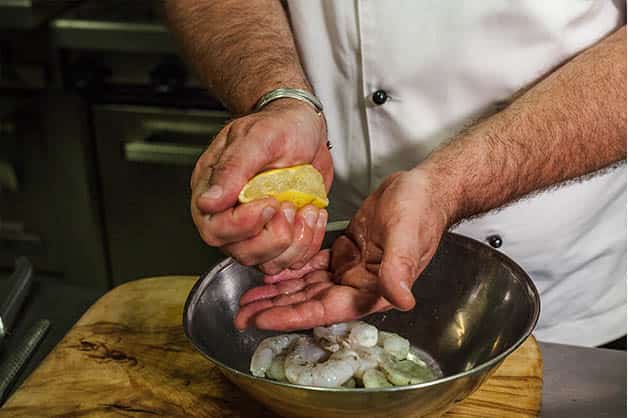 Squeezing lemon on prawns