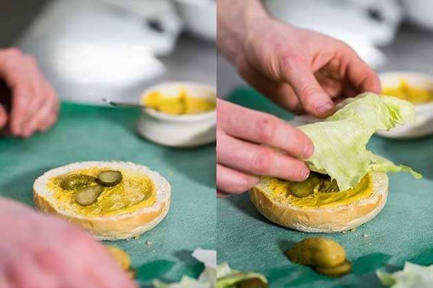 Photo of the pickles and lettuce being added to the bun