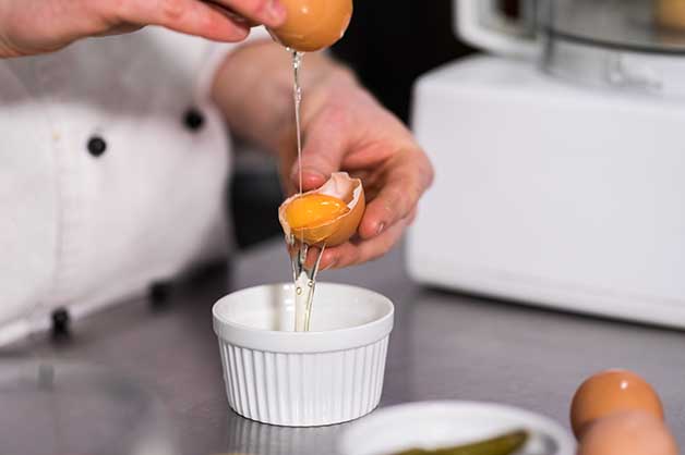 Chef cracking eggs into a bowl