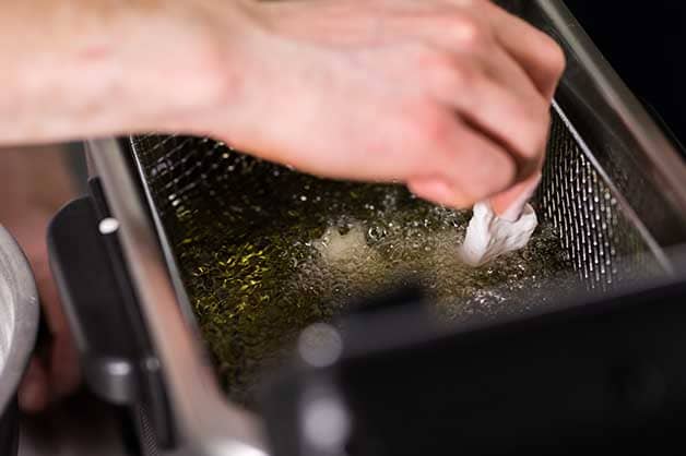 Chef deep frying the battered fish