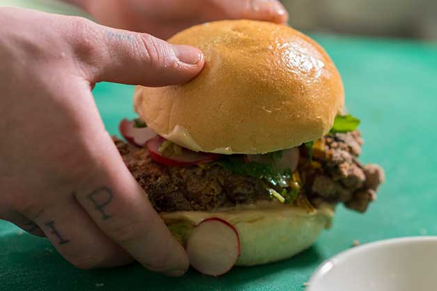 The chef finishes off the burger and presents it for plating