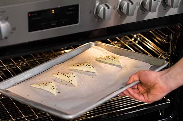 Chef is placing the triangles in the oven