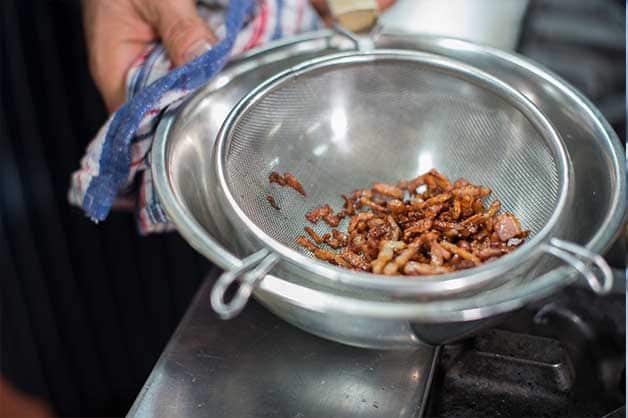 Here, the chef is seen draining the excess oil from the oil