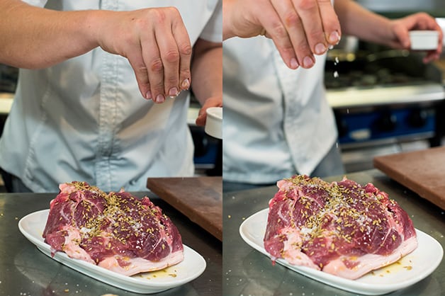 The photo shows the chef adding herbs to the pork shoulder