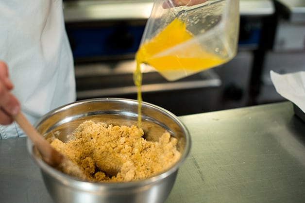 Image shows the chef combining the biscuit base with the butter