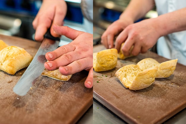 The chef is seen slicing the rolls after they came out of the oven