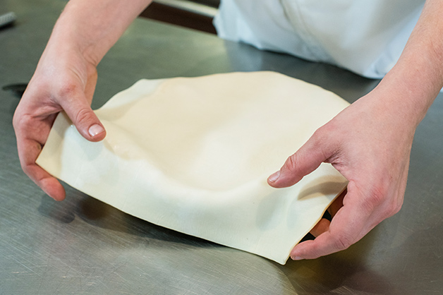 The chef is seen making a pastry lid for the pie