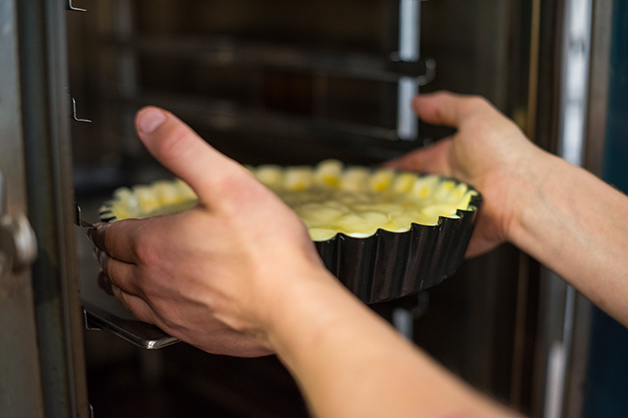 The chef is putting the apple pie into the oven