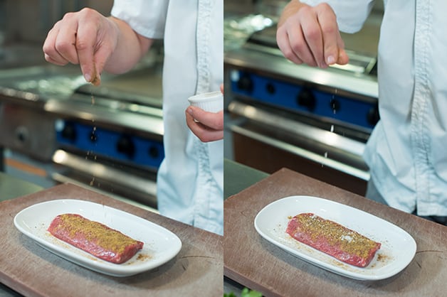 The chef is seen coating the lamb with dried spices