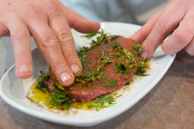 The chef is seen marinading the lamb