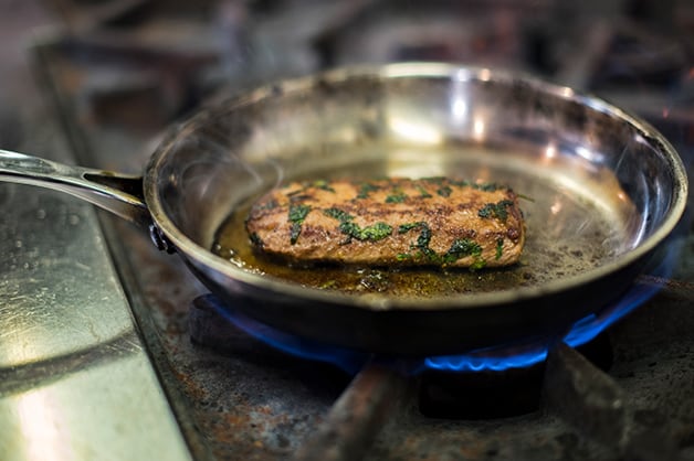 The chef is pictured turning the lamb steak