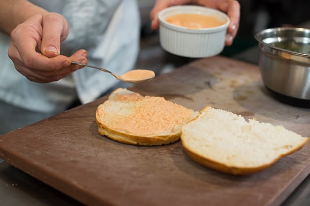 Here the chef is spreading the sauce on the bottom of the Turkish bread