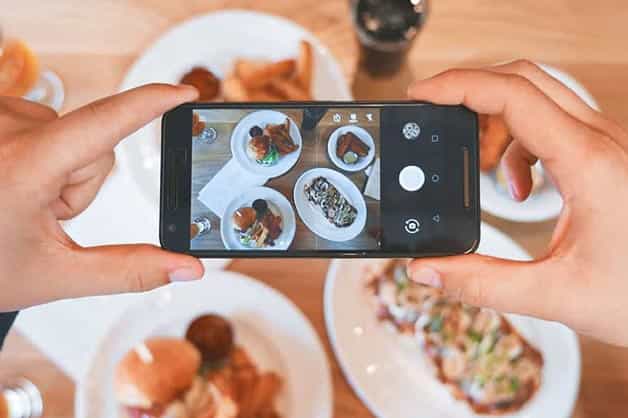 Someone is seen taking an image of food and posting it to social media