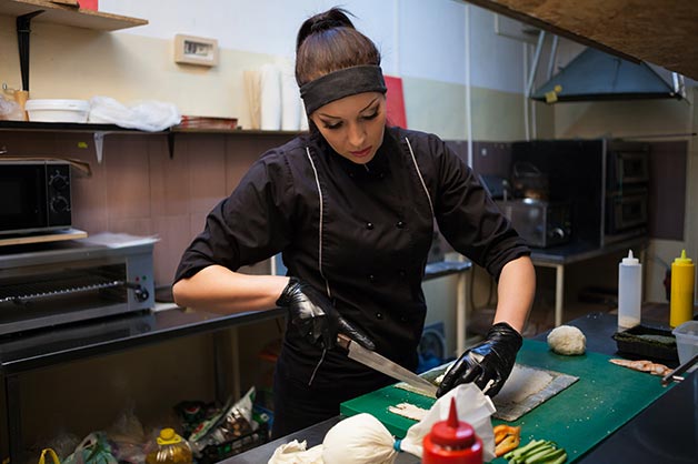 Female chef slicing food in the kitchen