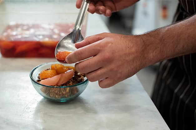 Adding the poached fruit on the muesli