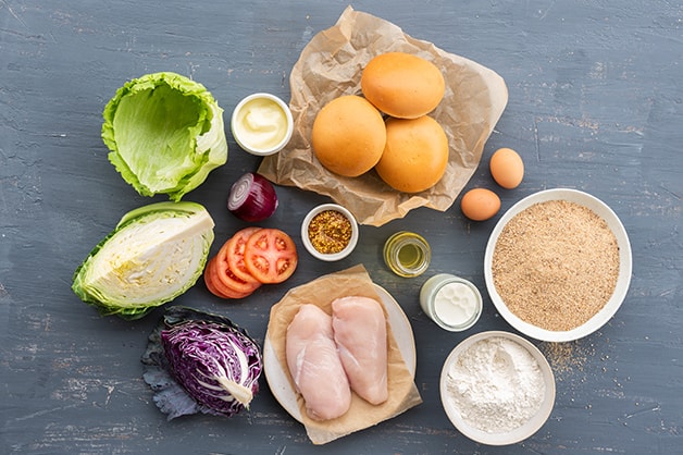 All the raw ingredients for the chicken schnitzel and slaw burger layed out on a mat