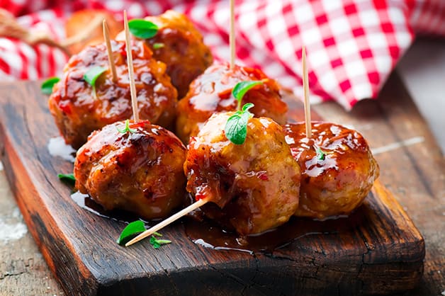 Image shows meatballs covered with sauce and with toothpicks