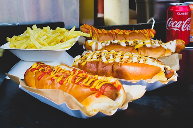 Photo shows four hot dogs covered in sauce