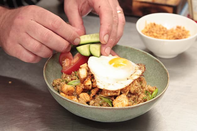 Image of the chef adding a fried egg to the dish