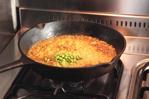 Chef is shown adding mustard seeds to the pan