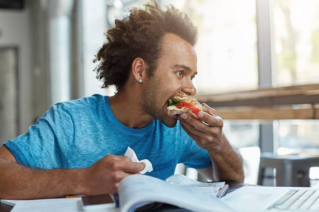 Man eating at a cafe while working