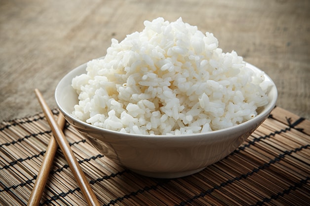 White rice is a bowl with chop sticks