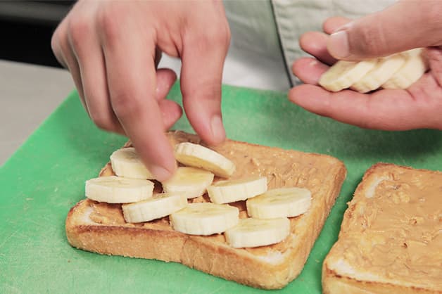 Adding the sliced banana to the peanut butter toast