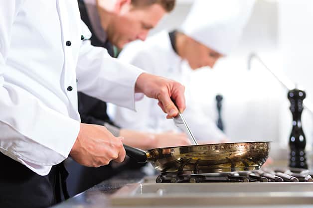 Chef teaching junior chef skills